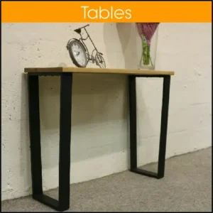 A table with a wooden top and black metal legs, sitting against a wall.