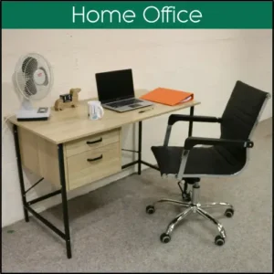 A small desk with a laptop and fan on, with an empty office chair.