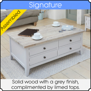 Close up of a grey coffee table sitting on a mat in a living room.